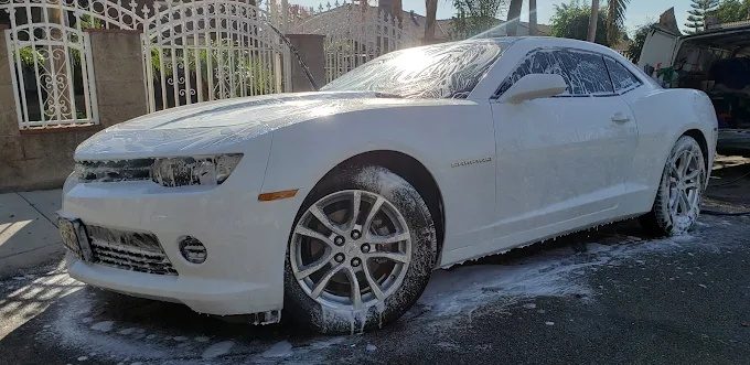 White Chevrolet Camaro covered in thick foam during a mobile car wash in Phoenix